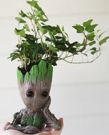 Handmade tree-man planter with trailing ivy, held in hand